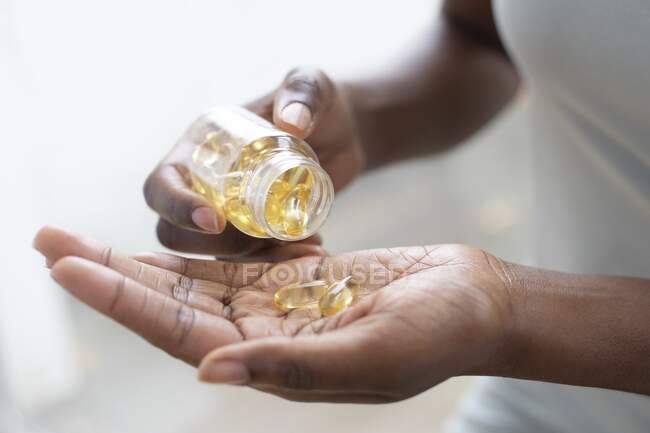Woman pouring capsules into her hand. — Stock Photo