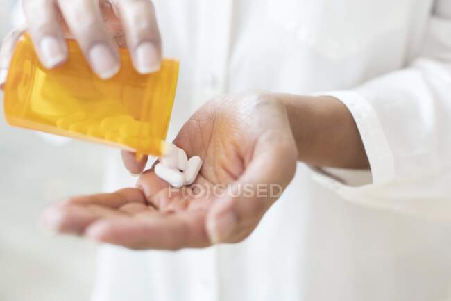 Mulher derramando pílulas em sua mão. — Fotografia de Stock