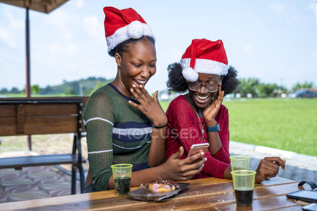 Amigos riéndose mirando un teléfono inteligente. - foto de stock