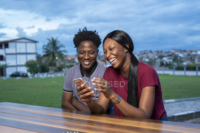 Lachende Freunde beim Blick aufs Smartphone. — Stockfoto