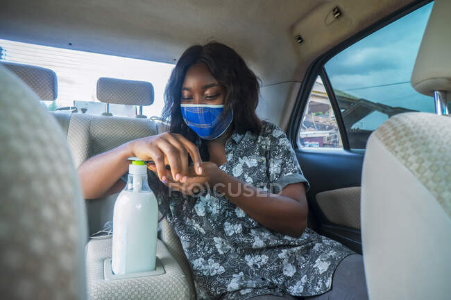 Frau benutzt Händedesinfektionsmittel im Taxi. — Stockfoto