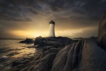 Lighthouse, water waves and rocks — Stock Photo