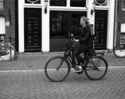 Ámsterdam, Países Bajos - 18 de junio de 2016: vista lateral de la mujer en bicicleta en Ámsterdam - foto de stock