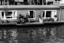 Amsterdã, Holanda - 18 de junho de 2016: Casal sentado no alpendre da casa flutuante — Fotografia de Stock