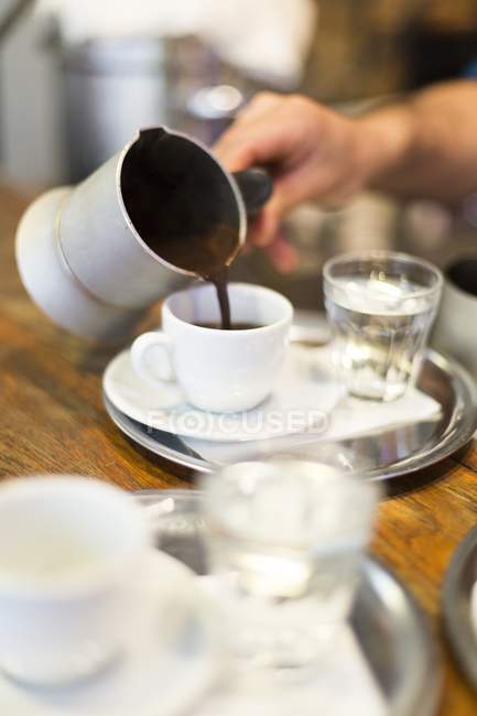 Человек наливает кофе в чашку — стоковое фото