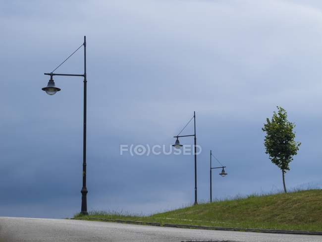 Тяжелые облака и сельская дорога с фонарными столбами — стоковое фото