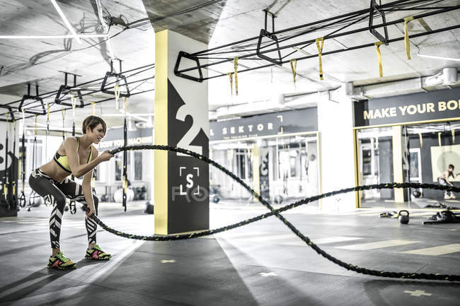 Chica hace ejercicio con cuerda de fitness en el gimnasio - foto de stock