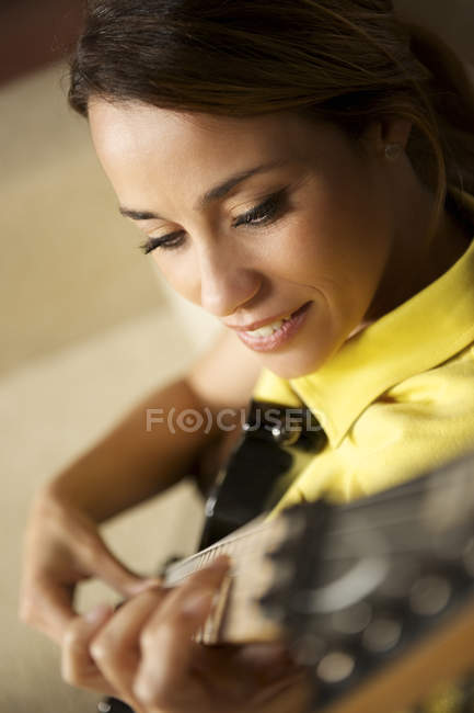 Femme jouant et s'entraînant avec guitare électrique à la maison — Photo de stock