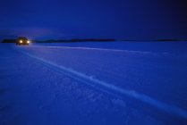 Auto mit Scheinwerfern auf Schnee — Stockfoto