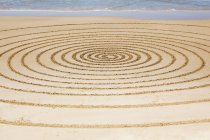 Círculos na areia contra a água — Fotografia de Stock