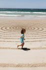 Giovane ragazza che corre lungo la sabbia — Foto stock