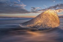 La lumière du coucher du soleil brille à travers un morceau de glace — Photo de stock