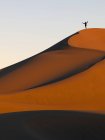 Человек стоит на вершине хребта песчаного склона на открытом воздухе в дневное время — стоковое фото