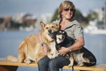 Жінка в сонцезахисні окуляри обіймаючи її собаки — стокове фото