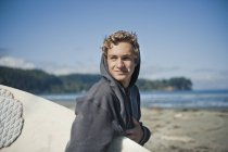 Молодой человек носит доску для серфинга — стоковое фото