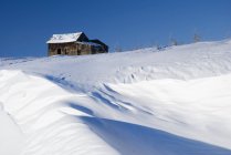 Edifício abandonado da fazenda no topo de uma colina nevada — Fotografia de Stock