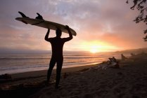 Hombre llevando tabla de surf - foto de stock