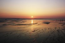 Puesta de sol sobre la playa de arena - foto de stock