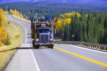 Camion d'exploitation forestière dans la route vide. Alberta, Canada — Photo de stock