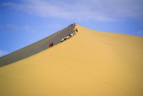 Pessoas escalando a duna de areia — Fotografia de Stock