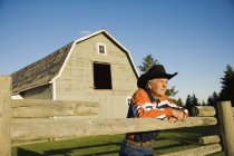 Ganadero apoyado en el Corral en la granja rural - foto de stock