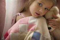 Girl With Teddy Bear with blanket indoors — Stock Photo
