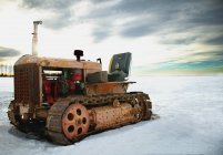 Старый трактор припаркован на снегу — стоковое фото