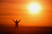 El hombre adorando a Dios contra el sol - foto de stock