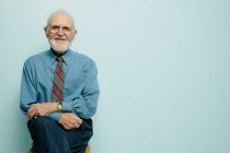 Ritratto di uomo anziano seduto e sorridente alla macchina fotografica — Foto stock