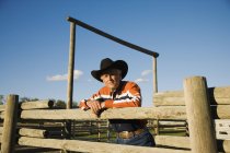 Ganadero apoyado en el Corral en la granja rural - foto de stock