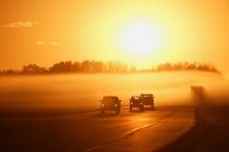 Carros na estrada contra o sol — Fotografia de Stock