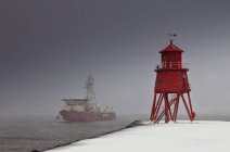 Faro rojo en la orilla - foto de stock