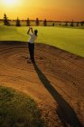 Vista posteriore del golfer che prende l'oscillazione dal bunker di golf — Foto stock