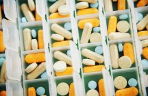 Diferentes pílulas médicas sortidas em recipiente — Fotografia de Stock