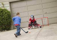 Deux garçons caucasiens jouant au hockey de rue — Photo de stock
