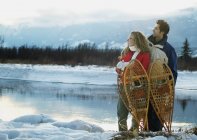 Couple With Snowshoes standing against lake — Stock Photo
