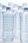 Linha de garrafas de água transparentes no fundo branco — Fotografia de Stock