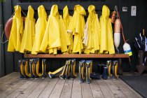 Capas de chuva amarelas e botas de borracha alinhadas — Fotografia de Stock