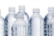 Ряд прозрачных бутылок воды на белом фоне — стоковое фото