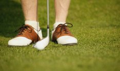 Imagem cortada de pernas masculinas em sapatos de golfistas com clube em curso — Fotografia de Stock