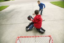 Due ragazzi caucasici che giocano a hockey su strada — Foto stock