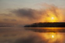 Sunrise over misty wilderness lake — Stock Photo