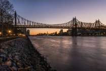 Pont au crépuscule sur l'eau de la rivière — Photo de stock