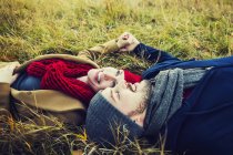Jovem casal deitado na grama e de mãos dadas no parque de outono — Fotografia de Stock