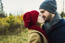 Young couple holding each other closely and kissing in city park — Stock Photo