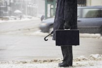 Abgeschnittenes Bild eines Geschäftsmannes im Mantel auf verschneiter Straße — Stockfoto
