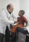Pequeño negro chico teniendo médico chequeo hasta - foto de stock