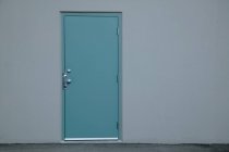 Closeup view of blue door in grey wall with copy space — Stock Photo