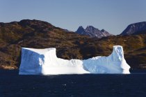 Iceberg en el agua contra la colina - foto de stock