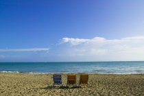 Песчаный пляж со стульями — стоковое фото